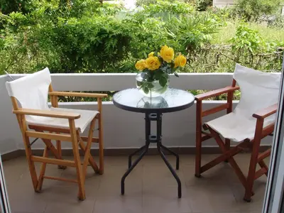 a table with chairs and a vase of flowers on a porch at Aris Apartments in Gerani Chanion