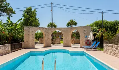 a swimming pool in a villa with a stone archway at Cretamos Seaside Villas in Kissamos