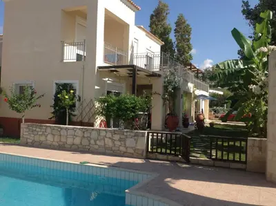 a villa with a swimming pool in front of a house at Cretamos Seaside Villas in Kissamos