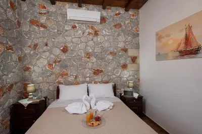 a bedroom with a bed with a stone wall at Sunset Traditional House in Ravdhoúkha