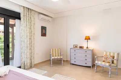 a bedroom with a bed and two chairs and a dresser at Villa Ismini in Kato Daratso