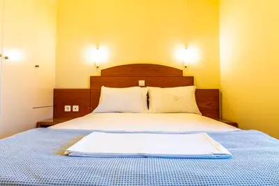 a bedroom with a bed with a wooden head board at Orestis Hotel Sea View Apartments in Stalos