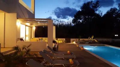a swimming pool with lounge chairs next to a house at Sea Queen Villa in Kato Daratso
