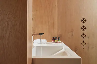 a bathroom with a white sink and a wooden wall at Domus Renier Boutique Hotel in Chania Town