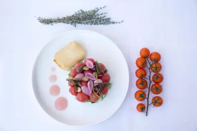 a white plate with a salad and a piece of bread and tomatoes at Thalassa Beach Resort & Spa (Adults Only) in Agia Marina Nea Kydonias