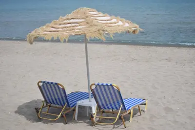 two chairs under an umbrella on the beach at Mesogios Beach in Kissamos