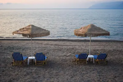 a group of chairs and umbrellas on a beach at Mesogios Beach in Kissamos