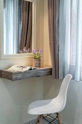 a white chair sitting in front of a mirror at Geana Apartments in Chania Town