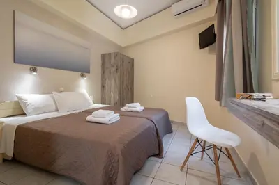 a bedroom with a bed and a chair and a tv at Geana Apartments in Chania Town