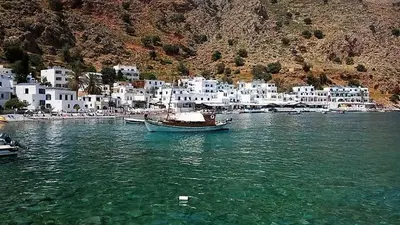 a boat in the water near a group of white buildings at Protopapas Rooms in Loutro