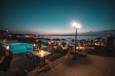 a group of people sitting at tables on a patio at night at Corinna Mare in Kalamaki Chanion