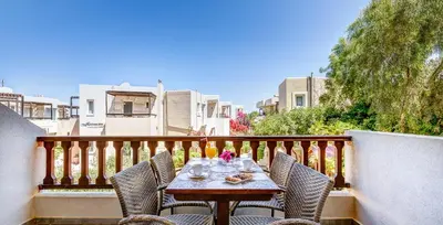 a table on a balcony with chairs and food on it at Corinna Mare in Kalamaki Chanion