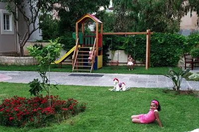 a little girl laying in the grass near a playground at Corinna Mare in Kalamaki Chanion