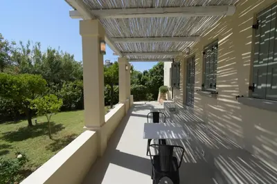 a porch with a pergola and benches on a house at Geraniotis Villa in Gerani Chanion
