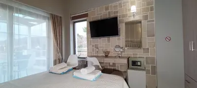 a bedroom with a bed with two chairs and a tv at Villa Alexandros in Kissamos