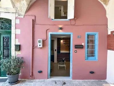 a pink house with a blue door at Sotoportego in Chania Town