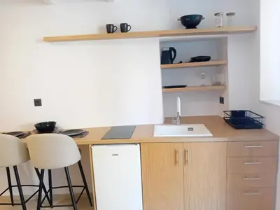 a kitchen with a sink and two bar stools at Sotoportego in Chania Town