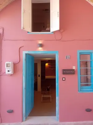 a pink and blue building with a blue door at Sotoportego in Chania Town