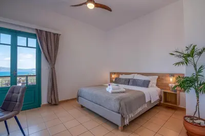 a bedroom with a bed and a chair and a window at Kaliviani Traditional Hotel in Kissamos
