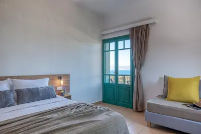 a bedroom with a bed and a couch and a window at Kaliviani Traditional Hotel in Kissamos