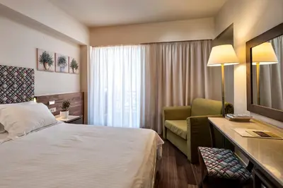 a hotel room with a bed and a chair at Civitel Akali Hotel in Chania Town