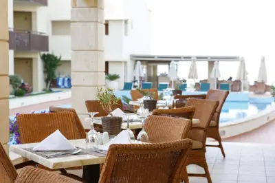 a restaurant with tables and chairs and a pool at Giannoulis - Santa Marina Plaza (Adults Only) in Agia Marina Nea Kydonias