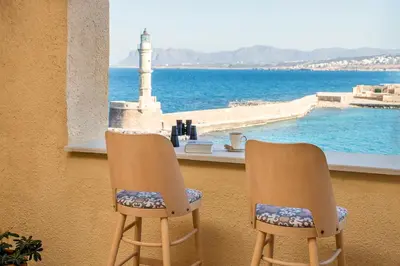 two chairs sitting in front of a window with a lighthouse at San Salvatore Monastery in Chania Town