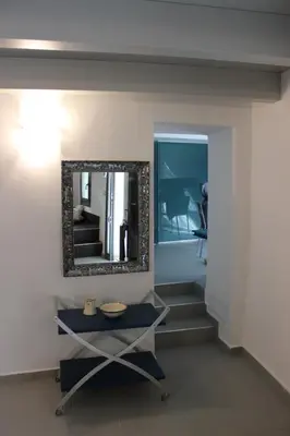 a room with a mirror and stairs with a table at Chorio House Platanias in Vrísai