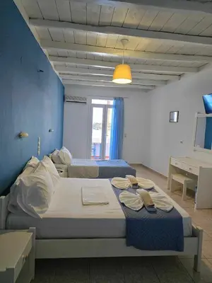 a bedroom with two beds and a blue wall at Faros Rooms in Loutro