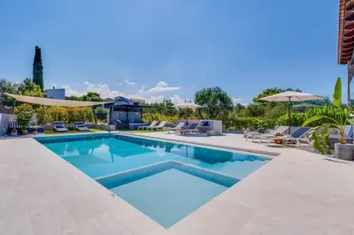 a swimming pool with chairs and umbrellas at Villa Ampelaki - Premium Villa with heated pool in Kounoupidhianá