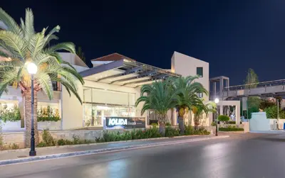 a building with palm trees in front of a street at Iolida Beach by Smile Hotels in Agia Marina Nea Kydonias