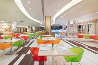 a restaurant with tables and colorful chairs in a room at Iolida Beach by Smile Hotels in Agia Marina Nea Kydonias