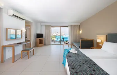 a hotel room with a bed and a desk at Iolida Beach by Smile Hotels in Agia Marina Nea Kydonias