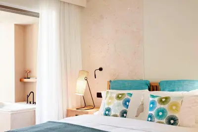 a bedroom with a bed with blue and white pillows at Domes Noruz Chania, Autograph Collection- Adults Only in Kato Daratso