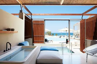 a bedroom with a tub and a view of the ocean at Domes Noruz Chania, Autograph Collection- Adults Only in Kato Daratso