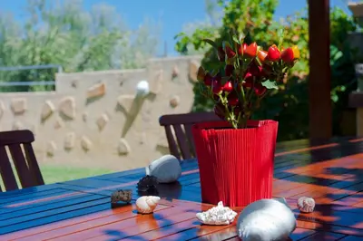 a red vase with a bouquet of flowers on a table at Villa Aretousa 2 in Agia Marina Nea Kydonias