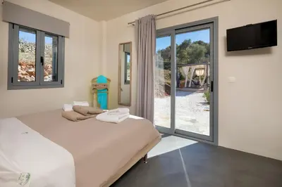 a bedroom with two beds and a sliding glass door at Villa di Lusso Agave con Piscina Privata Riscaldata e Jacuzzi in Litsárdha