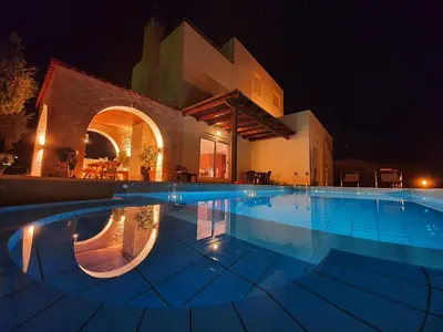 a swimming pool in front of a building at night at Argo Villa Kalives in Kalyves