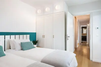 a white bedroom with two beds and a hallway at Happy Villa in Kato Galatas