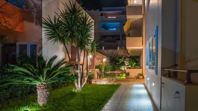 a courtyard with palm trees in a building at night at Vakakis-ME Apartments in Palaiochóra