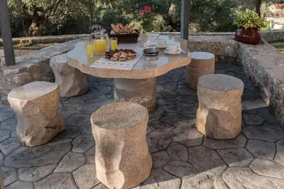a stone table and stools with a table and some drinks at Villa Fabrica in Thimiá