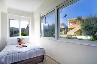 a bedroom with a bed and two large windows at Domus Creta in Kato Daratso