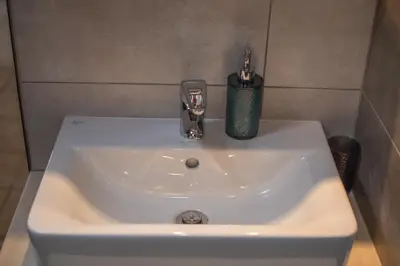 a bathroom sink with a soap dispenser on it at Grameno Apartments in Kountoura Selino