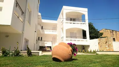 a large vase sitting in the grass in front of a house at Crown Apartments in Kalyves