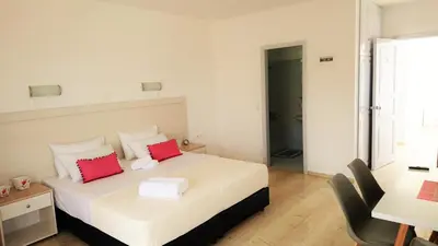 a bedroom with a bed with two red pillows at Crown Apartments in Kalyves