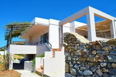 a white house with a stone wall at Villa-Palaiochora in Palaiochóra