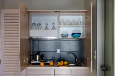 a kitchen with white cabinets and a sink with fruits at Blue Horizon in Palaiochóra