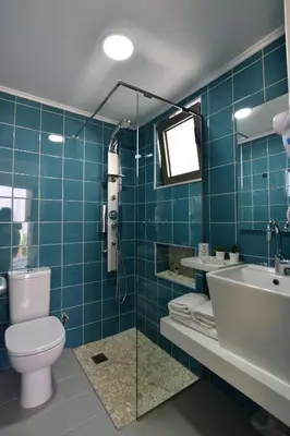 a blue tiled bathroom with a toilet and a sink at Blue Horizon in Palaiochóra