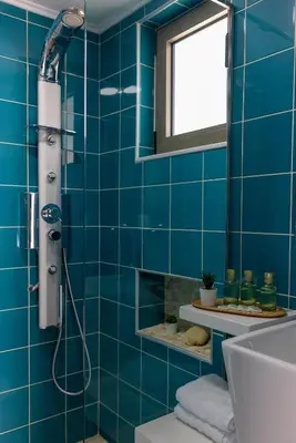 a blue tiled bathroom with a shower and a sink at Blue Horizon in Palaiochóra