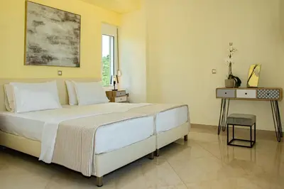 a bedroom with a large white bed and a table at Villa Dimokratia in Kolymvari